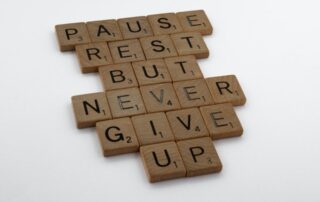 Scrabble tiles saying Pause rest but never give up in support to the article - Having trouble losing weight.